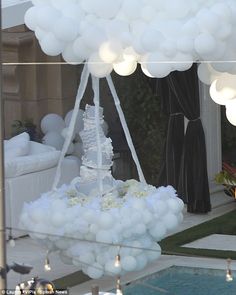 a white cake is surrounded by balloons in the shape of a boat on top of a pool