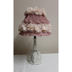 a lamp that is on top of a white table with pink and white flowers in the shade