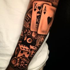 a man's arm with playing cards and dice tattoo on his left upper arm