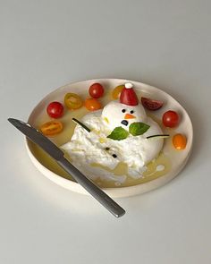 a white plate topped with fruit and a snowman shaped dish next to a spoon