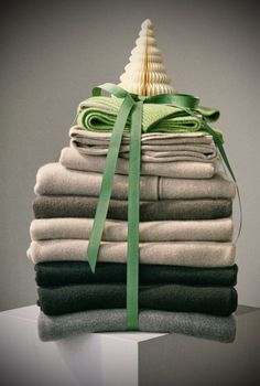 a stack of folded clothes with a green ribbon tied around the top and on top