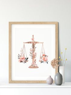 a framed photograph of a scale with flowers on it and a vase next to it