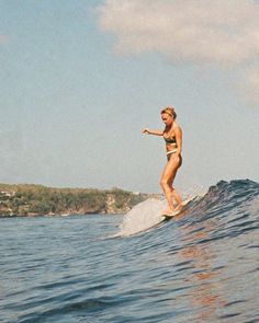 a woman riding a wave on top of a surfboard