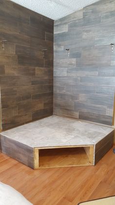 an empty room with wood flooring and tile on the walls, including a corner shelf