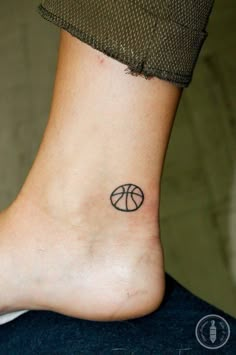 a small tattoo on the ankle of a person with a basketball ball in it's center