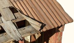 a bird is perched on the roof of a wooden structure with rusted shingles