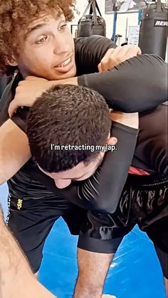 two men are wrestling in a ring with one holding the other's arm around his head