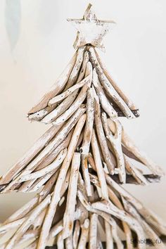 a small wooden christmas tree made out of driftwood sticks with a star on top