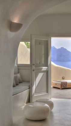 an open door leading into a living room with white walls and floor to ceiling windows