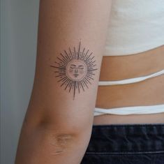 a woman's arm with a small sun tattoo on the left side of her arm