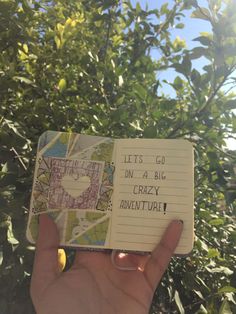 someone is holding up a small notebook with the words let's go on a big crazy adventure