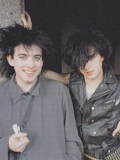 two people standing next to each other with hair on their head and one holding something in his hand