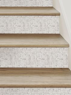 a close up view of some stairs with tile on the wall and wood flooring