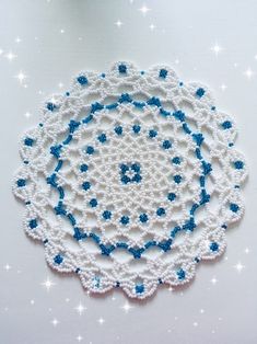 a crocheted doily with blue and white flowers on it, surrounded by stars