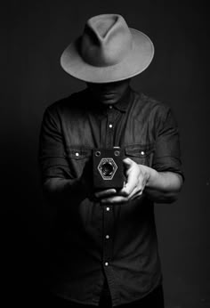 a man wearing a hat and holding a camera in his hands, with one hand