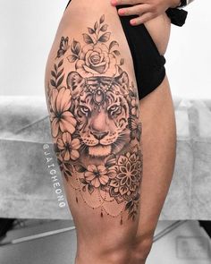 a woman's thigh with a tiger and flowers tattoo on the side of her leg