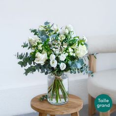 a vase filled with white flowers sitting on top of a table next to a chair