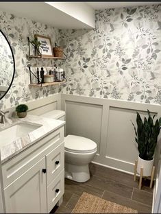 a white toilet sitting next to a sink in a bathroom under a large round mirror