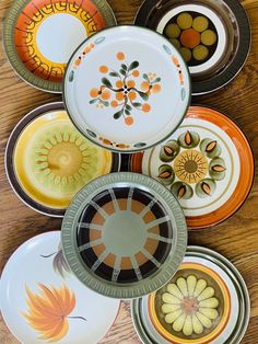 many plates are stacked on top of each other in different colors and designs, including oranges and browns