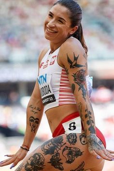 a woman with tattoos on her body is sitting in the middle of a race track