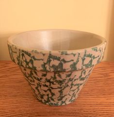 a white and green bowl sitting on top of a wooden table