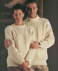 two people in sweaters and pants standing next to each other with their arms around one another