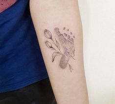 a woman's arm with a tattoo on it that has flowers and a hand print