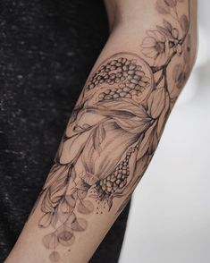 a woman's arm with flowers and leaves tattooed on the arm, in black and white