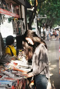 a woman standing in front of a book stand with her head down on the table