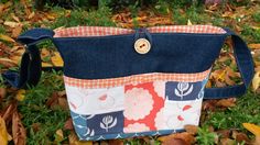 a patchwork purse sitting on top of leaves in the grass with a gold button