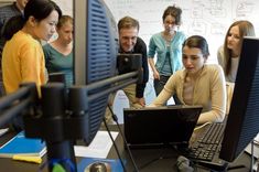 a group of people standing around a laptop computer