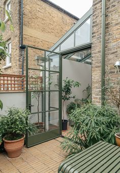 an outdoor patio with potted plants and a bench in the foreground, surrounded by brick buildings