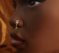 a close up of a woman's face wearing ear rings with green stones on them