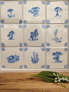 blue and white ceramic tiles with flowers on the counter next to them, including lily of the valley