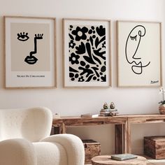 three black and white paintings hang on the wall above a chair in a living room