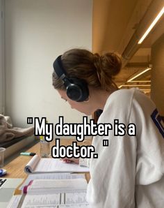 a woman sitting at a desk with headphones on, reading a book and listening to music