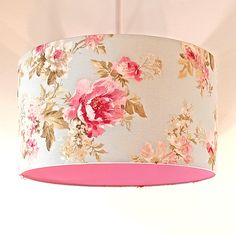 a pink and white flowered lamp shade hanging from a ceiling fixture in a room