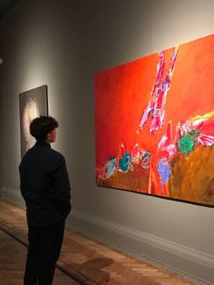 a woman looking at paintings on display in an art gallery