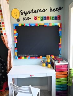 a white desk topped with a blackboard and lots of legos on top of it