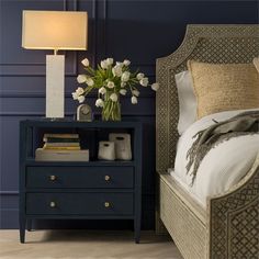 a bedroom with blue walls and white flowers on the night stand next to the bed