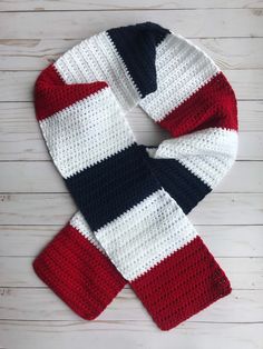 a red, white and blue knitted scarf sitting on top of a wooden floor