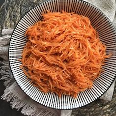 a white bowl filled with shredded carrots on top of a table