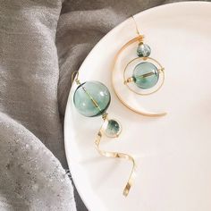 Longues boucles d'oreilles dépareillées en métal doré et bulles de verre bleu.  imposantes mais légères, ces boucles d'oreilles sont originales et ne passent pas inaperçues. la boucle, tout en longueur, avec la torsade en métal doré mesure 10 cm. la perle bleue, en verre, environ 2 cm (photo 4). la boucle avec l'arcade, plus large, mesure 9 cm. la perle en verre mesure environ 1.5 cm (photo 5). d'autres petites fantaisies, perles, apprêts bijoux, agrémentent les boucles d'oreilles. Bubble Earrings, Green Bubble, Korean Earrings, Glass Drop Earrings, Fairy Jewelry, Magical Jewelry, Mismatched Earrings, Fresh Green, Glass Ball