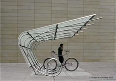 a man standing next to a bike in front of a building with an open roof