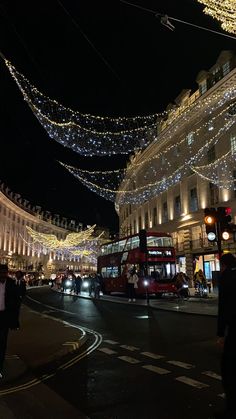 a busy city street is lit up with christmas lights