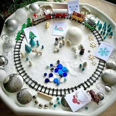 a train track with christmas ornaments and cards on the tracks in front of it, sitting on a table