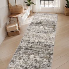 a white and gray area rug in a room with wood flooring, potted plants and window