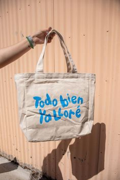 a person holding a tote bag with the words too many tollore written on it