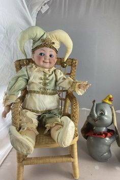 a baby doll sitting in a chair next to an elephant figurine