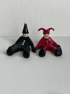 two small black and red figurines sitting next to each other